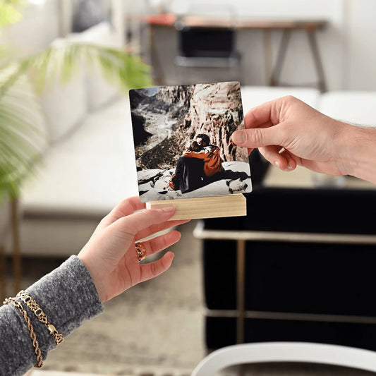 Metal desk print of a couple sitting together at a canyon overlook, held above a wooden stand in a bright living room setting.