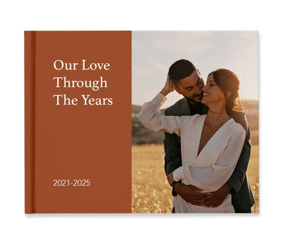 Hardcover photo book cover with couple embracing in golden field, featuring split-color layout and year range text.