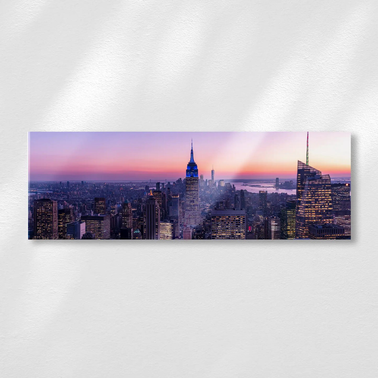Acrylic wall print displaying a panoramic New York City skyline at sunset with illuminated buildings and a gradient sky over the urban landscape.