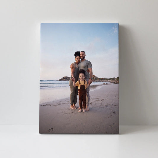 Canvas desk print of two adults and a child standing together on a sandy beach, displayed against a clean white background.
