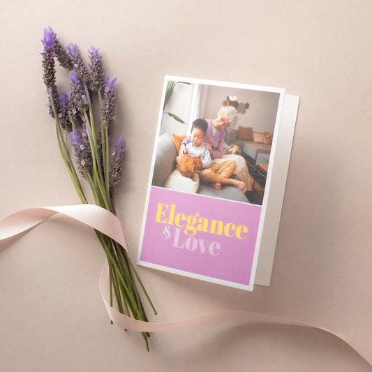 Folded greeting card with family photo and “Elegance & Love” text, placed beside lavender stems and ribbon on a neutral background.