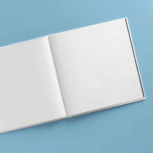 Open hardcover photo book with blank pages on a blue background