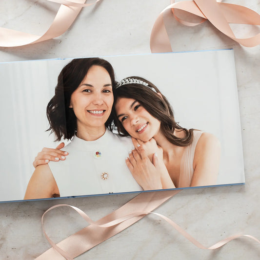 Layflat photo book open to a full-page portrait of a woman and young girl smiling together against a clean, light background