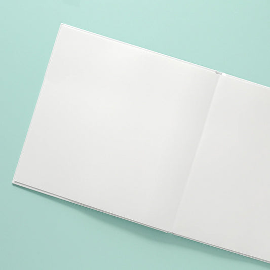 Open layflat photo book with blank pages on a teal background