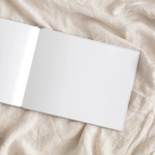 Open layflat photo book with blank pages on a light beige fabric