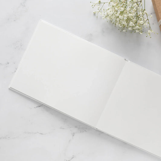 Open layflat photo book with blank pages on a marble background