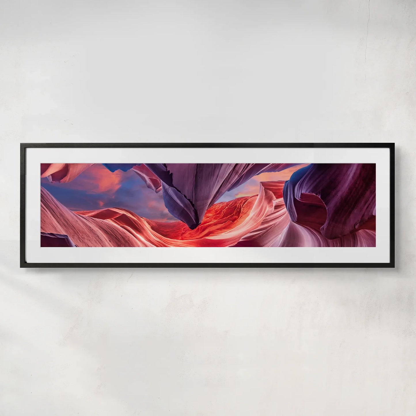 Wide framed panoramic print showcasing abstract canyon rock formations in vivid red and purple tones, displayed on a minimalist wall.