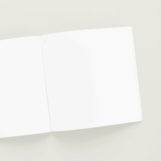 Open softcover photo book with blank pages on a light gray background