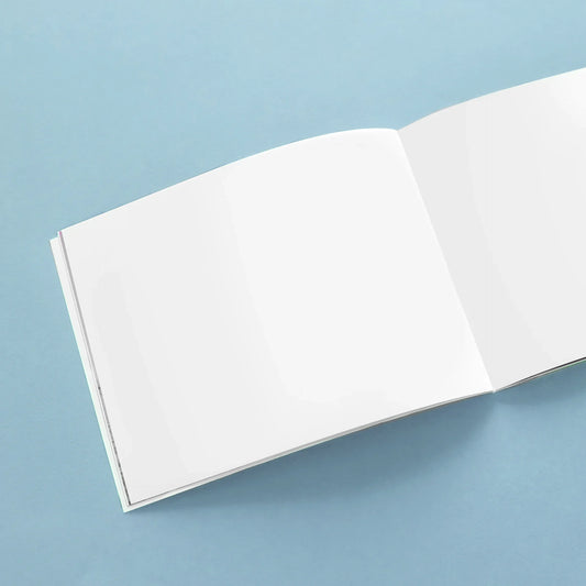 Open softcover photo book with blank pages on a blue background
