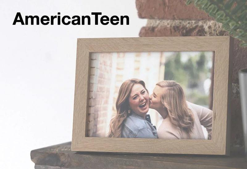 Wooden picture frame displaying a photo of two friends laughing together outdoors on a tabletop, with the AmericanTeen logo.