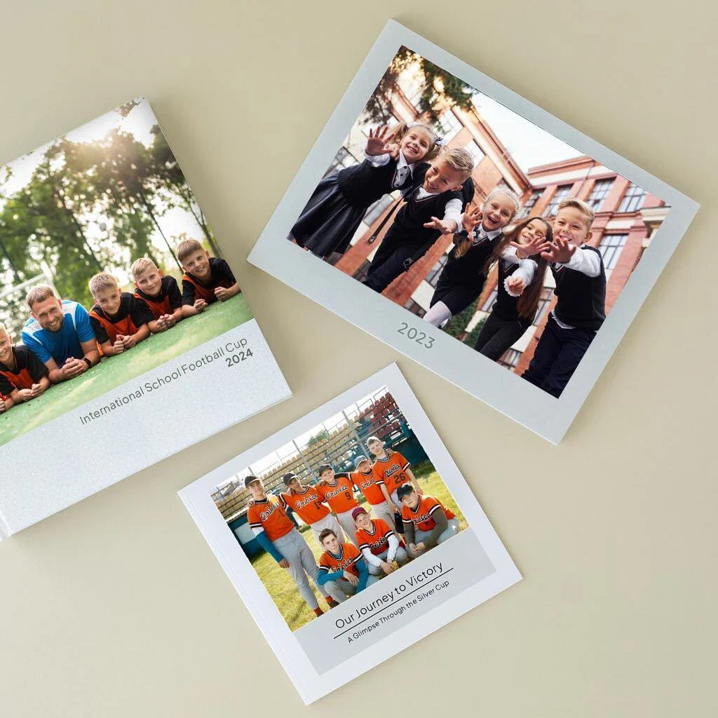 Three custom photo books laid flat, featuring school and sports team covers with titles and year labels.